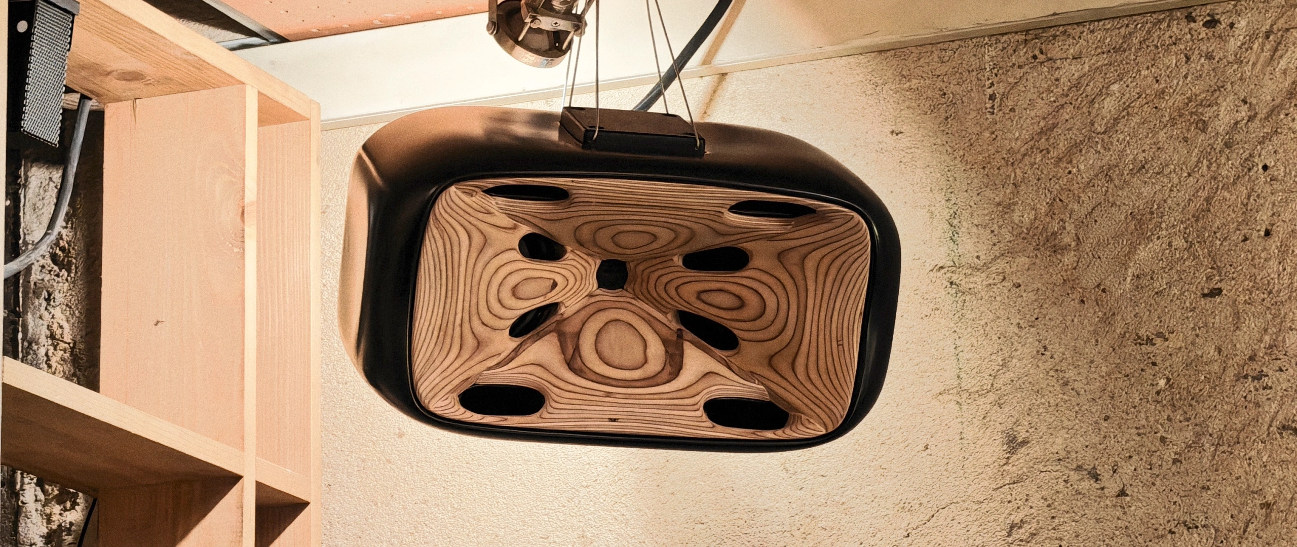 A Cohérence 5 hung from the ceiling on steel cables, the birch horn inside its black shell